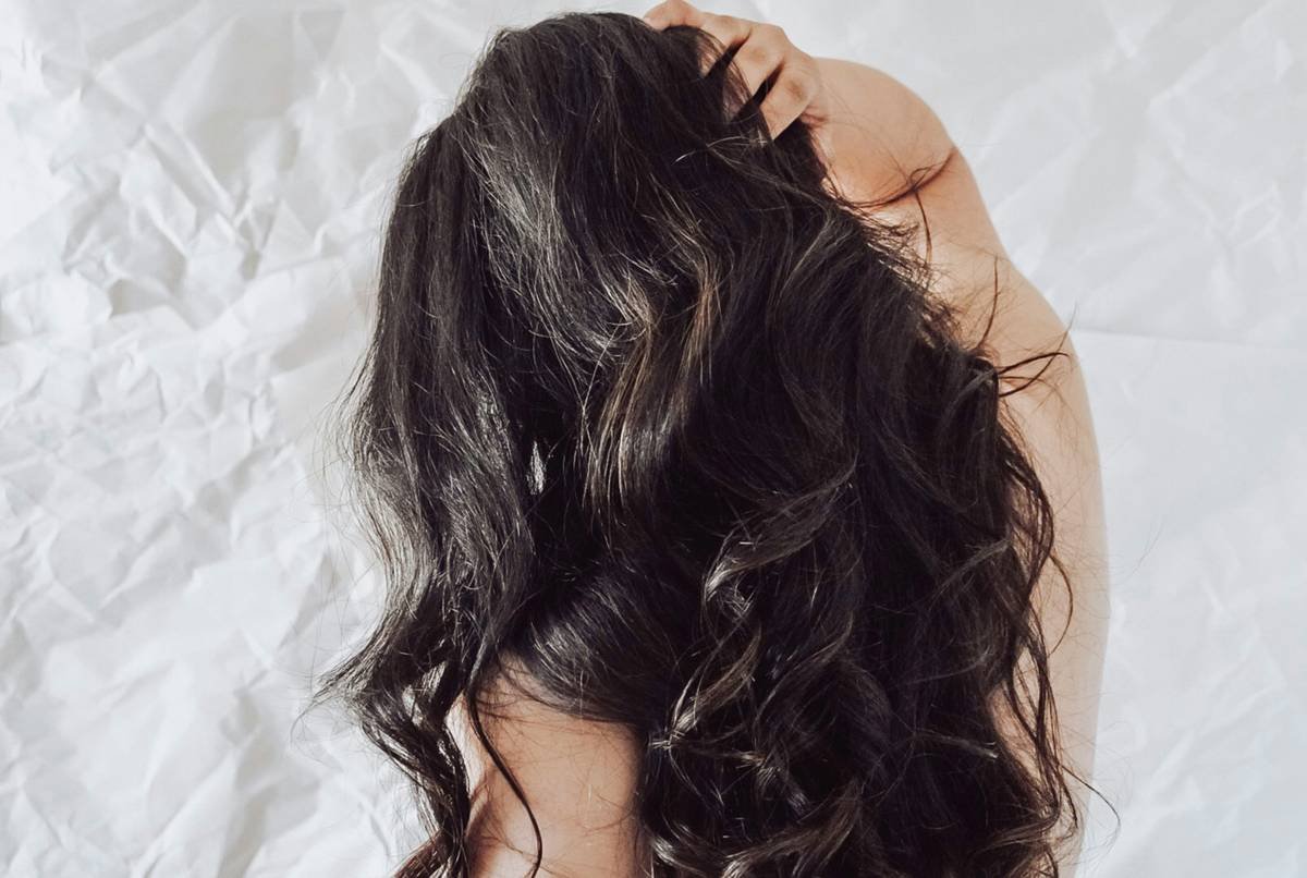Woman applying homemade conditioning hair solution with avocado and honey
